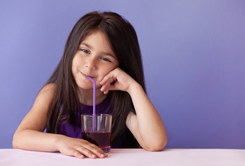 Cute little brunette girl drinking fresh juice