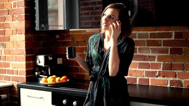 Young, beautiful woman talking on cellphone in the kitchen
