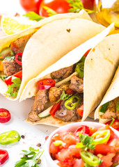 Mexican pork tacos with vegetables and salsa on white.