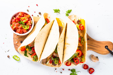 Mexican pork tacos with vegetables and salsa on white.