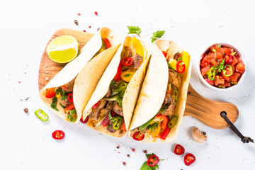 Mexican pork tacos with vegetables and salsa on white.