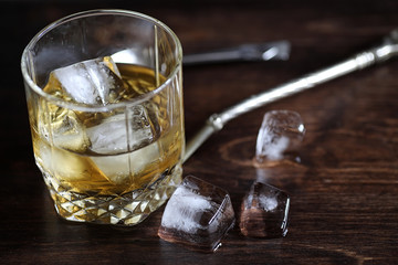 Whiskey in a glass and pieces of ice on a wood