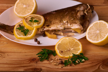 Appetizing baked fish, covered with juicy lemons, garlic and salt on side, above view