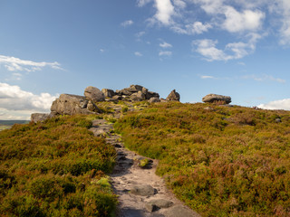 Naklejka premium Path leading to a hilltop covered in rock formations near the peak districts stanage edge