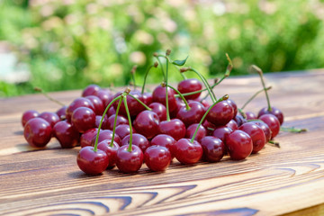 The heap of  ripe red cherries on the wooden table on open air. Seasonal healthy food. Close-up view. Copy space for text.