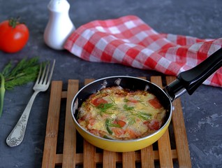 Lush omelette or frittata with garlic arrows and tomatoes in a portioned pan