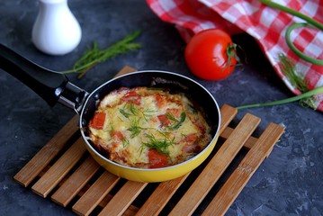 Lush omelette or frittata with garlic arrows and tomatoes in a portioned pan