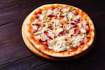 Pizza with salami and gherkins. Delicious meal with lots of vegetables, tasty nutritional food. Restaurant menu photography, mediterranean and american cuisine