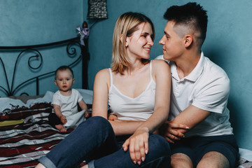 Parenthood, relationships, children, marriage concept. Young couple hugging and baby daughter at background