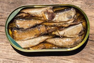 Open tin can of sprats on rustic wooden table