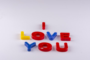 colored uppercase letters isolated forming the phrase i love you made of plastic on white background with shadows
