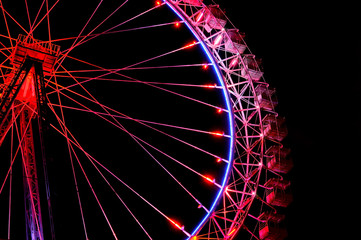 Big ferris wheel with festive red illumination against night sky.