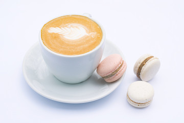 Coffee latte in a white mug and dessert macaroons on a white background.