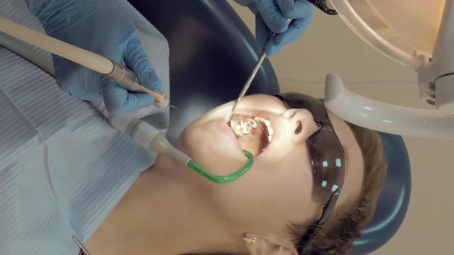 Woman at the dentist clinic office gets dental medical examination and treatment. Odontic and mouth health is important part of modern human life that dentistry help with. Vertical format video.