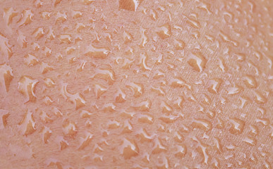 the texture of  human skin is covered with large drops of fresh shiny water