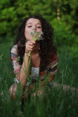 Young woman with dark curly hair. Young woman with dandelions in hands.