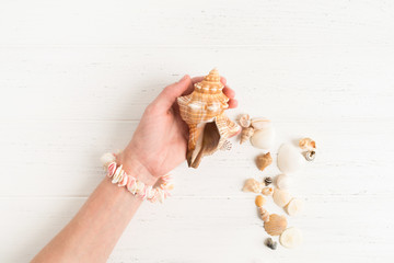 Female hand holds a big shell on the wooden background