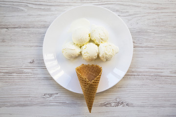 Sweet ice cream cone with ice cream scoops on a white plate, top view. From above.