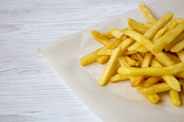 French fries on a white wooden surface, closeup.