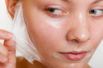 Woman removing facial peel off mask closeup