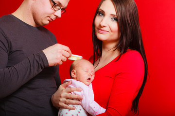 Newborn on mother chest, father brushing baby hair