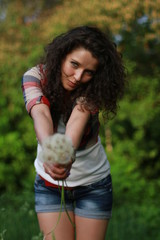 Young woman with dark curly hair. Young woman with dandelions in hands.