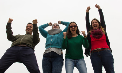Obraz premium Three girls and man with arms up in sign of victory. Group of friends celebrating victory. Soccer enthusiast fans, football supporters concept