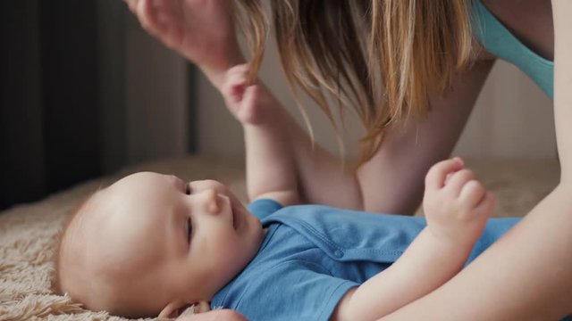 Mother and child on bed. Mom and baby boy in diaper playing in sunny bedroom. Parent and little kid relaxing at home. Family having fun together. Kissing kiss newborn close up closeup