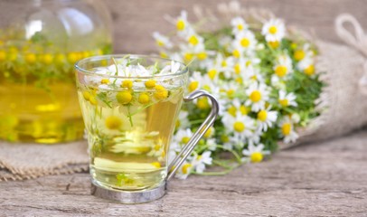 cup of chamomile tea with chamomile flowers on wooden planks 