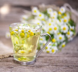 cup of chamomile tea with chamomile flowers on wooden planks 