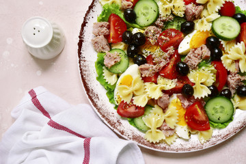 Pasta salad with tuna, cherry tomatoes, cucumber, black olives and boiled eggs.Top view.