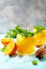 Cold summer orange lemonade with mint and ice cubes.