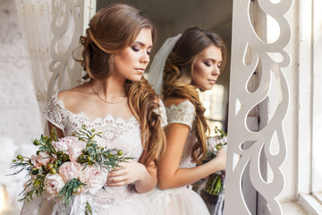 Naklejka premium A bride with hairstyle and make up in gorgeous pink wedding dress and a vail with a bouquet of peonies. A portrait of beautiful girl with brunette hair and blue eyes in studio