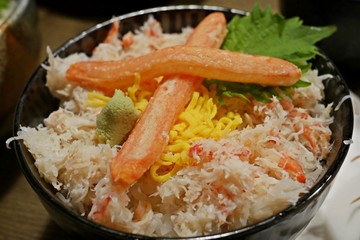 Tasty and delicious Donburi or Japanese rice bowl topped with boiled Kani(crab) garnished with wasabi and shredded fried egg at restaurant. Closeup. Selective Focus. Healthy Eating, Eat Well Concept.