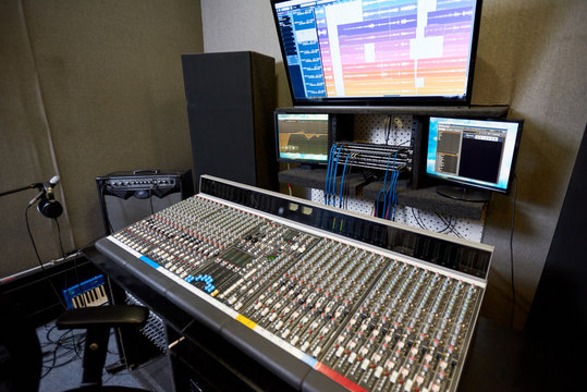 Interior shot of modern control console and monitors in contemporary music recording studio. 
