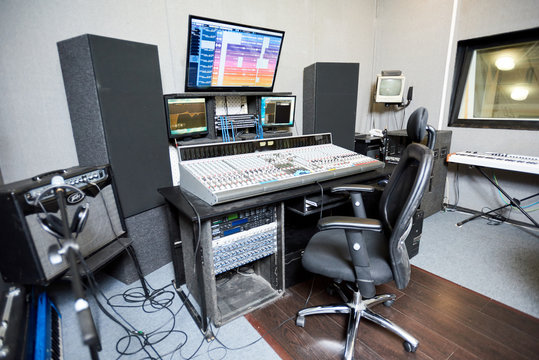 Interior shot of small studio with big console and monitors for creative music. 