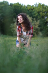 Fototapeta premium Young, beautiful woman on nature. Young woman with dark curly hair.
