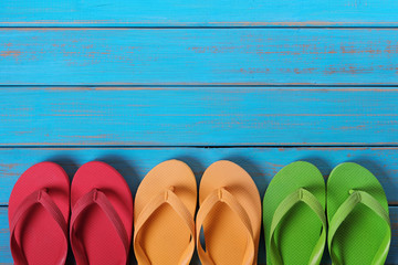 Flip flops in a row old weathered blue beach wood background