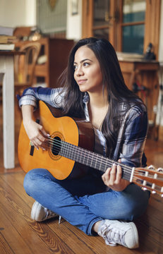hispanic young woman playing acoustic guitar