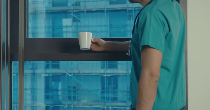 Doctor drinking coffee by the window in hospital