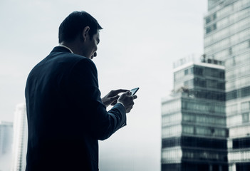 businessman using mobile phone near office window at office building,online business concept.