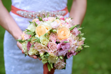 Obraz na płótnie Canvas Beautiful bride is holding a wedding colorful bouquet