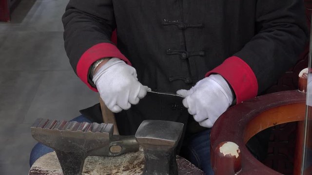 Craftsman manually makes silverware at Qianmen Street. Beijing, China