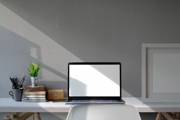 Loft workplace mockup poster with laptop, supplies and vintage books. Workspace and blank screen laptop.