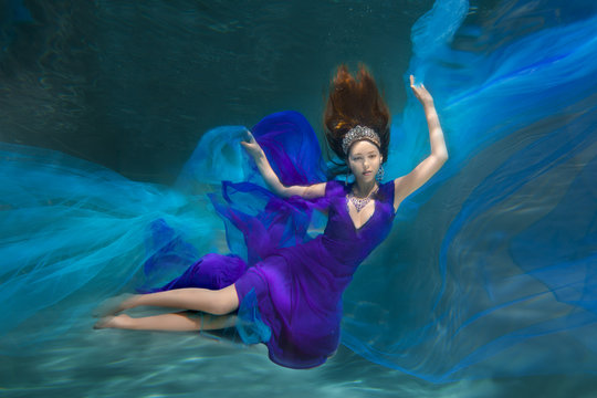 Underwater Queen. Girl mermaid. Underwater scene. A woman, a fashion model in the water in a beautiful dress swims like a fish.