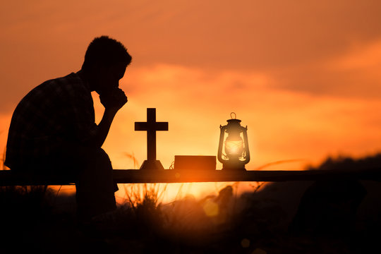 Boy Praying And Reading Holy Bible On Wood , Christian Silhouette Concept.