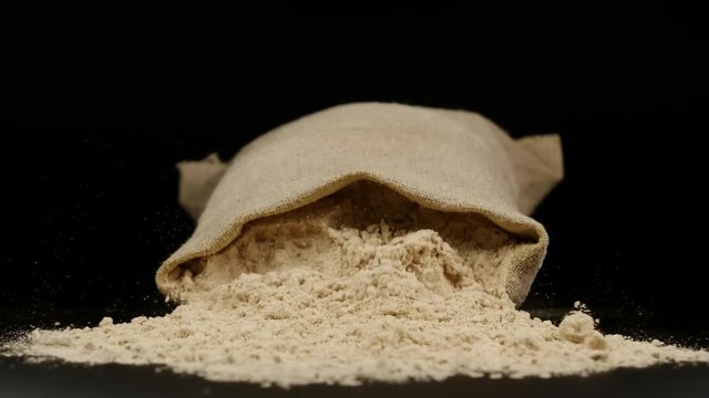 SLOW MOTION: A Sac with ginger powder fall on a table
