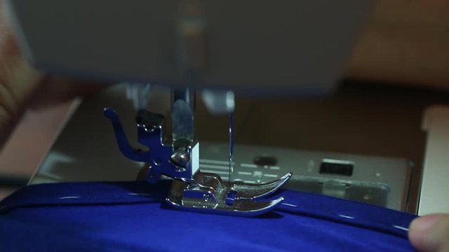 Close up of Hands of Hardworking European Elderly Woman, stitching fabric using Sewing Machine at her Workshop, Focused on working Process. Clothing, Design, dressmaking and tailoring