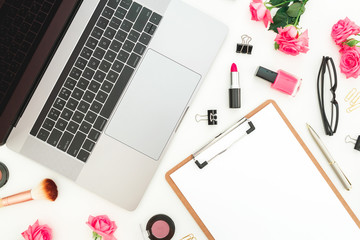 Laptop, clipboard, roses flowers, cosmetics and accessories on white background. Flat lay. Top view. Feminine freelancer composition