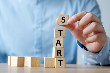 Man hand holding wooden cube with start word on table, business conceptual, sucess in business concept